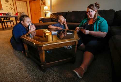 Kristina Hazeltine plays a game of Uno Dare with her children A.J. Wilson, 12, left, and Deacon Hazeltine, 6, center, at their home on Monday, Sept. 16, 2019, in Springfield, Mo.Hazeltine5