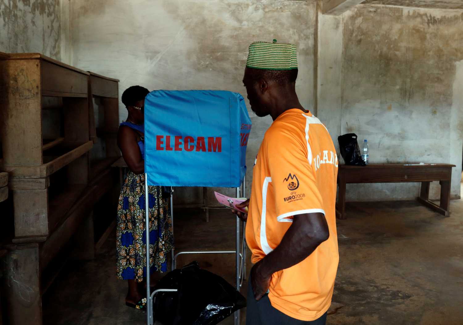 A woman casts her ballot as an another voter waits for his turn at a polling station during the presidential election, in Yaounde, Cameroon October 7, 2018. REUTERS/Zohra Bensem