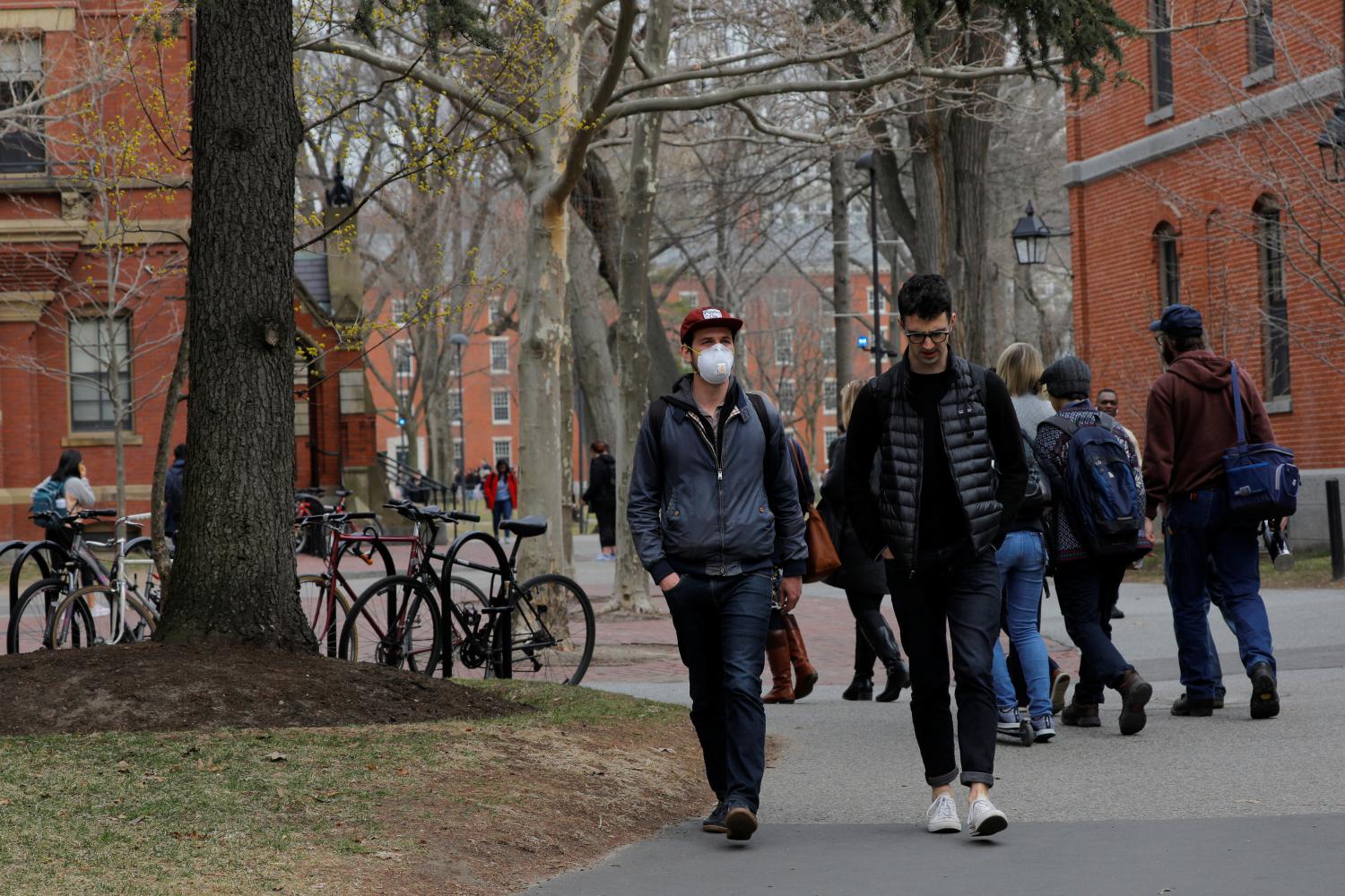 A student wearing a mask, because his cancer treatment has left him immunosuppressed and vulnerable to diseases such as the coronavirus, walks through the Yard at Harvard University, after the school asked its students not to return to campus after Spring Break and said it would move to virtual instruction for graduate and undergraduate classes, in Cambridge, Massachusetts, U.S., March 10, 2020.   REUTERS/Brian Snyder