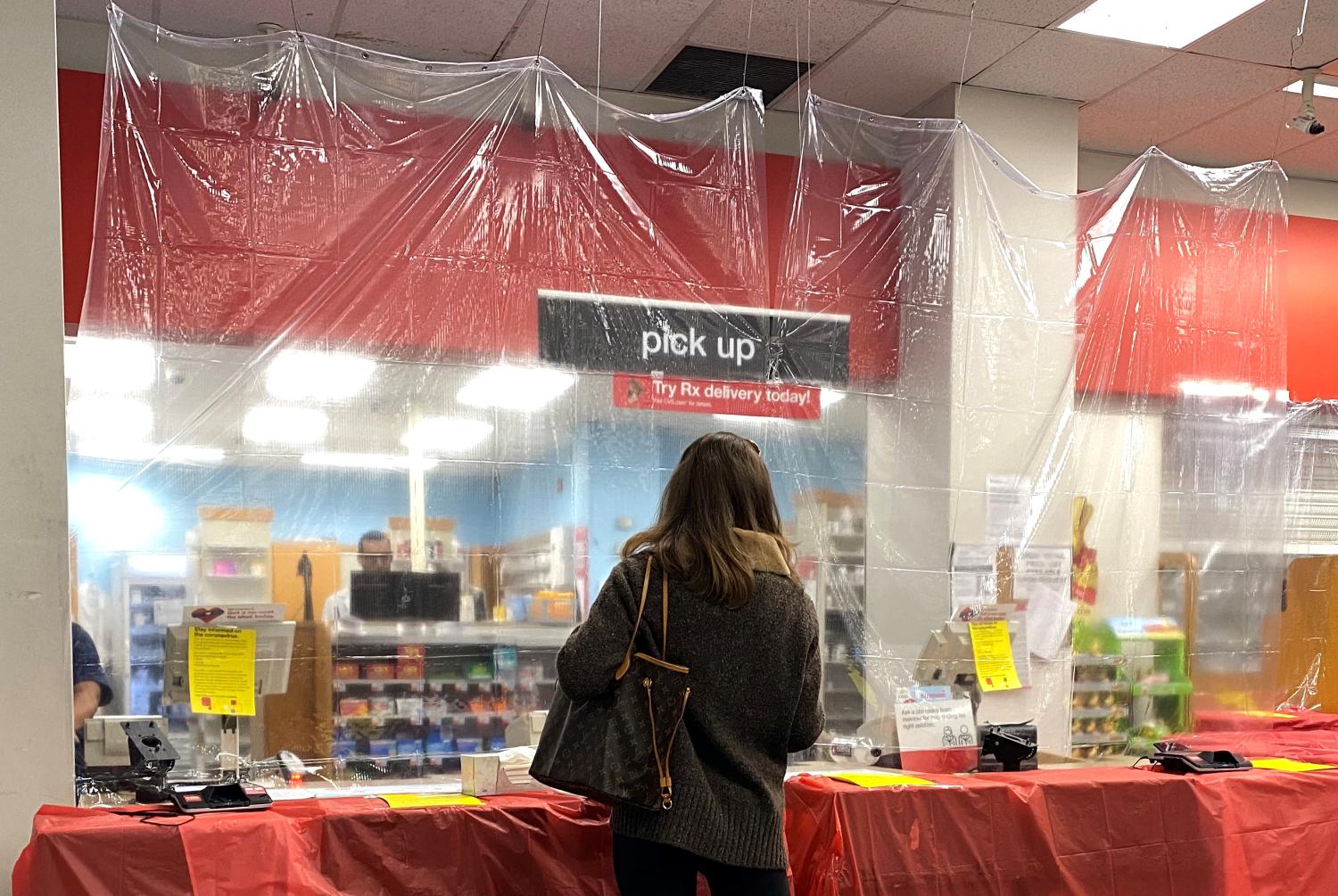 A woman waits behind a sheet of protective plastic at the pharmacist's counter at a CVS Pharmacy in Manhattan during the outbreak of the coronavirus disease (COVID-19) in New York City, New York, U.S., March 27, 2020. REUTERS/Mike Segar