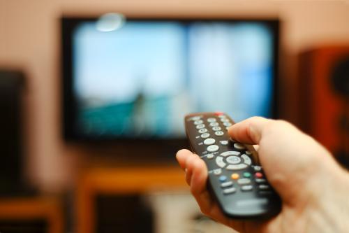 Image of someone holding up a remote pointed at a television screen.