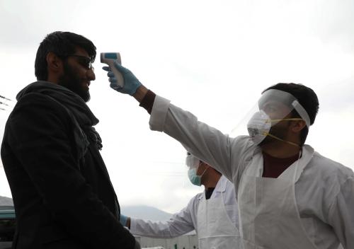 A medical official in protective gear checks the body temperature of a traveller, who arrives from provinces, amid concerns about the spread of coronavirus disease (COVID-19), in Kabul, Afghanistan March 24, 2020. REUTERS/Omar Sobhani