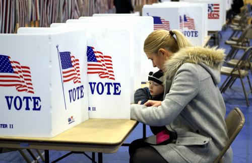 A woman marks her ballot with her child looking on in the presidential primary at Bedford High School in Bedford, New Hampshire February 9, 2016.   REUTERS/Rick Wilking