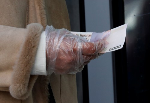 A woman wearing a plastic glove holds money as she stands in a queue to buy face masks at a post office, after a shortage of masks amid the rise in confirmed cases of the novel coronavirus disease COVID-19, in Daegu, South Korea, March 4, 2020. REUTERS/Kim Kyung-Hoon