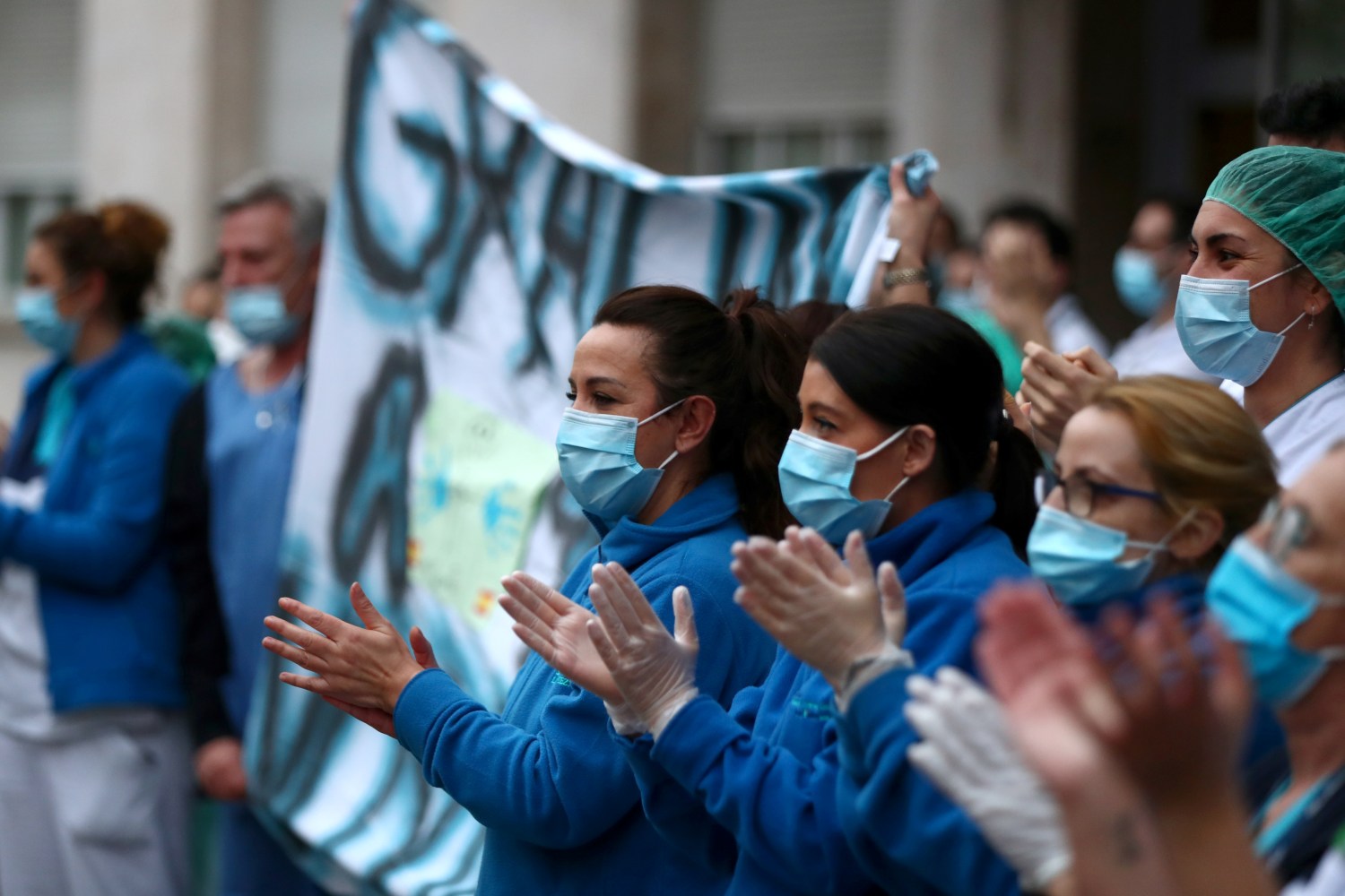 Medical staff from Fundacion Jimenez Diaz hospital react as neighbours applaud from their balconies in support for healthcare workers, amid the coronavirus disease (COVID-19) outbreak, in Madrid, Spain, March 30, 2020. REUTERS/Sergio Perez