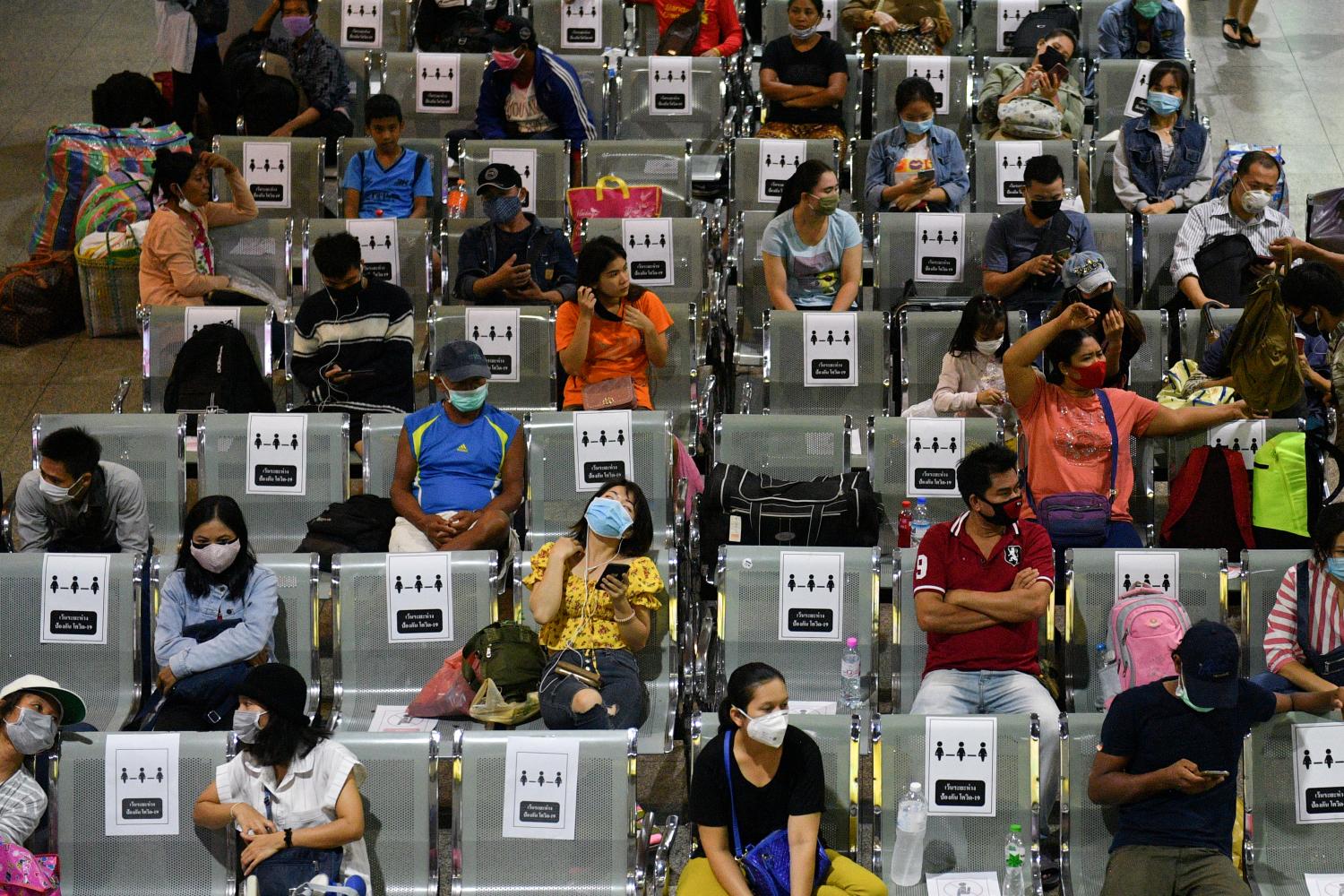 People wearing protective face masks, sit on social distancing benches at a bus station after many workers crowded the terminal station to return to their cities after many activities have been closed due to coronavirus disease (COVID-19) outbreak, Thailand March 22, 2020. REUTERS/Challinee Thirasupa     TPX IMAGES OF THE DAY