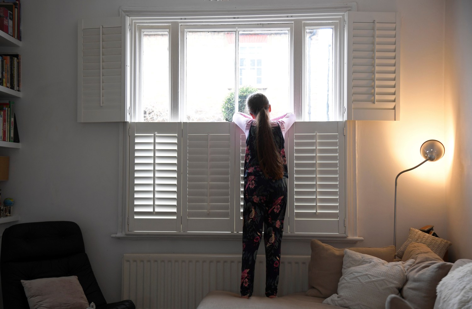 Nine-year-old Eve looks out of the front window at home, as the number of coronavirus disease (COVID-19) cases grow around the world, in London, Britain, March 17, 2020. REUTERS/Toby Melville