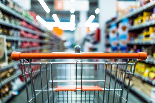 Abstract blurred photo of store with trolley in department store background. Supermarket aisle with empty red shopping cart