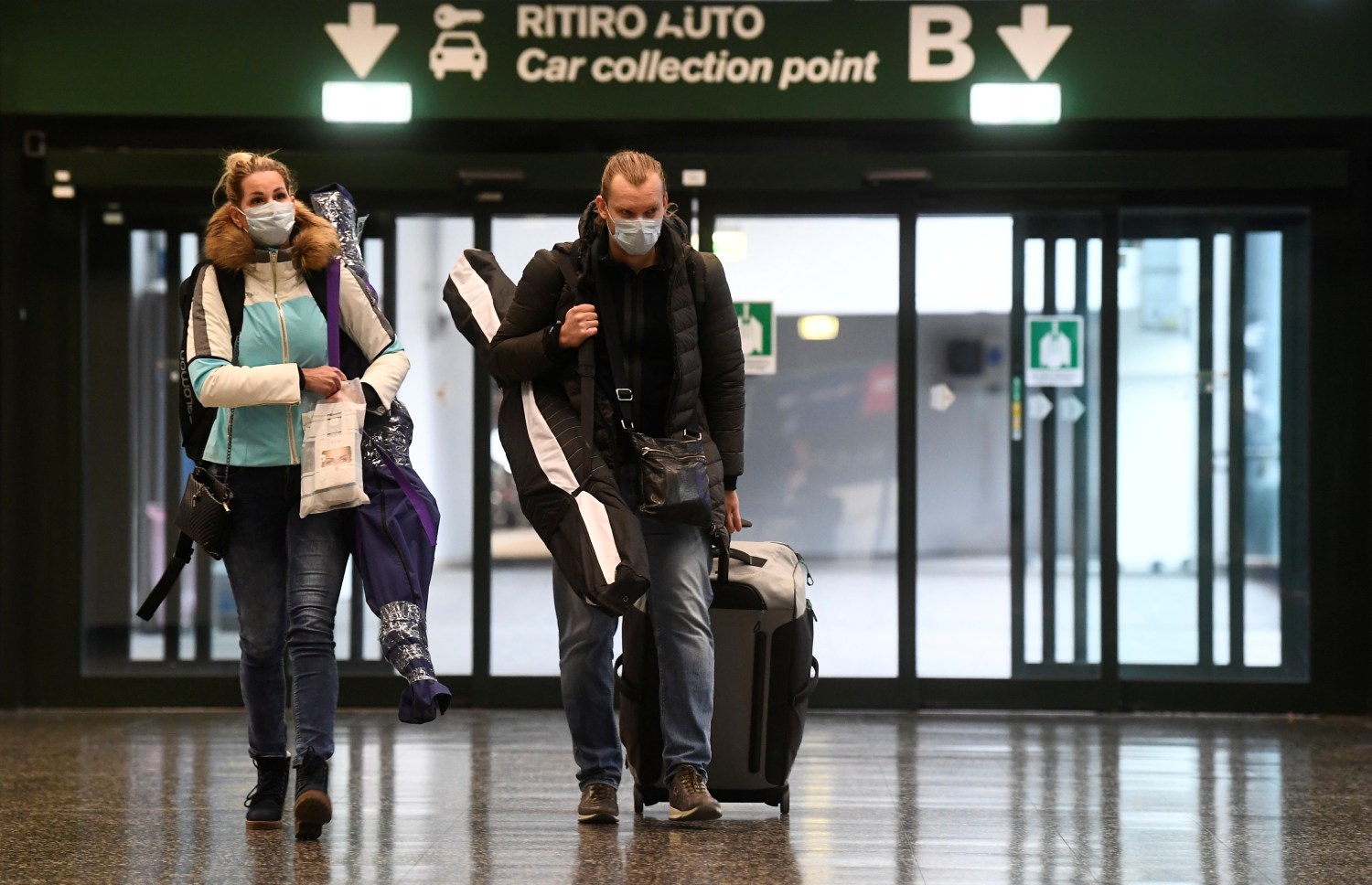 People wearing protective masks walk in Malpensa airport near Milan, Italy, March 9, 2020. REUTERS/Flavio Lo Scalzo