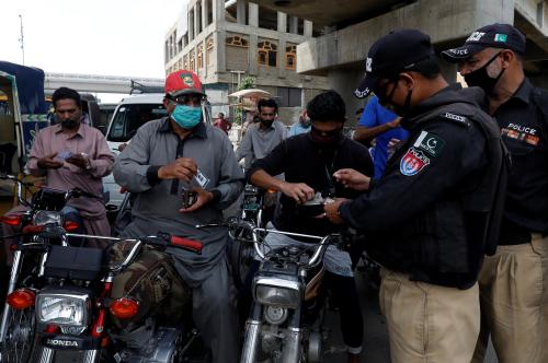 Police officers check identity cards of commuters before letting them cross a checkpoint during a partial lockdown after Pakistan shut all markets, public places and discouraged large gatherings amid an outbreak of coronavirus disease (COVID-19), in Karachi, Pakistan, March 24, 2020. REUTERS/Akhtar Soomro