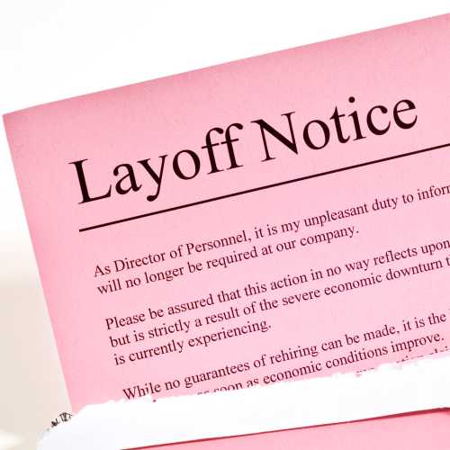 Close-up of layoff notice or pink slip in opened envelope.