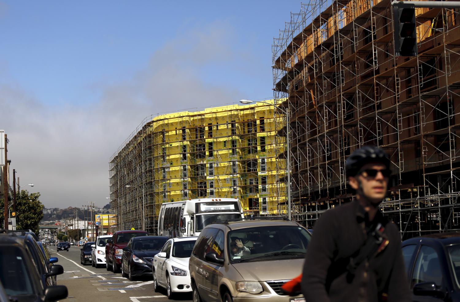 A bicyclist sits in traffic near a housing construction project in San Francisco, California June 2, 2015. The median rent for an apartment in the city is now $4,225 per month, according to local media. REUTERS/Robert Galbraith
