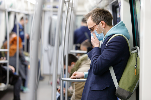 A man wearing a mask rides the subway