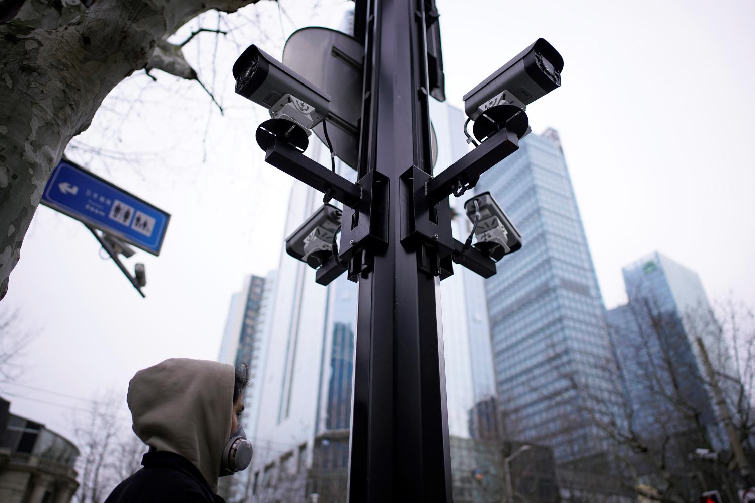 A man wearing a protective face mask walks under surveillance cameras as the country is hit by an outbreak of the novel coronavirus, in Shanghai, China March 4, 2020. REUTERS/Aly Song