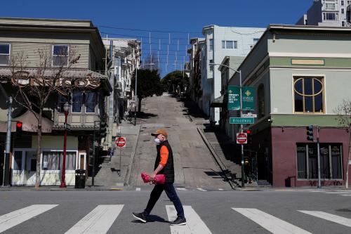 A man wearing a face mask walks across the street, a day after California's Governor Gavin Newsom implemented a statewide "stay at home order" directing the state's nearly 40 million residents to stay in their homes for the foreseeable future in the face of the fast-spreading coronavirus disease (COVID-19), in San Francisco, California, U.S. March 20, 2020. REUTERS/Shannon Stapleton