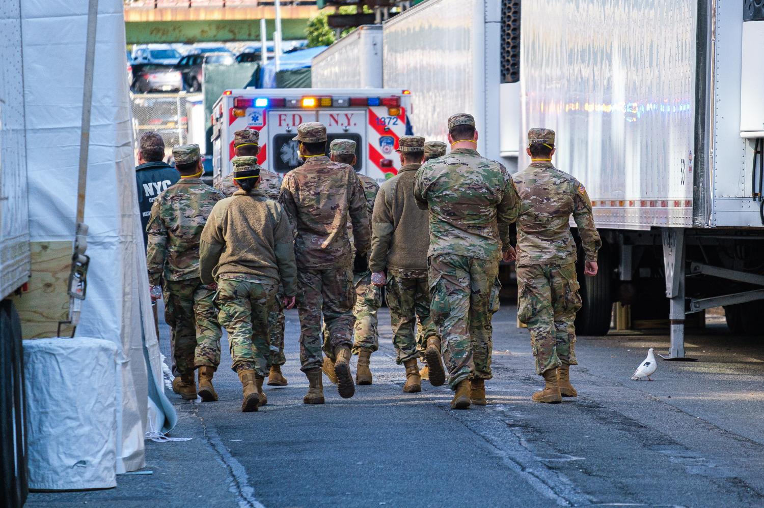 A Medical Examiner's Office employee and a unit of National Guard members walk near refrigerated trailers used as morgues on East 3oth Street near the Office of the New York City Chief Medical Examiner as the city prepares for a surge of COVID-19 cases requiring medical treatment; in New York , NY, USA on Wednesday, April 1, 2020.  (Photo by Albin Lohr-Jones/Sipa USA)No Use UK. No Use Germany.
