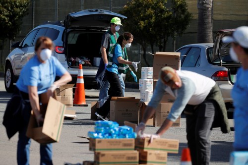 A volunteer helps fill cars with food and home staples as the Jacobs and Cushman San Diego Food Bank helps thousands at a drive through food bank during the outbreak of the coronavirus disease (COVID-19) in Del Mar, California, U.S., April 3, 2020.      REUTERS/Mike Blake