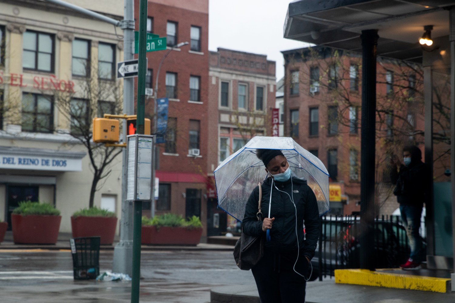A woman wearing a protective mask carries wait for a bus during the outbreak of the coronavirus disease (COVID-19) in the Brooklyn borough of New York City, U.S., April 26, 2020. REUTERS/Jeenah Moon
