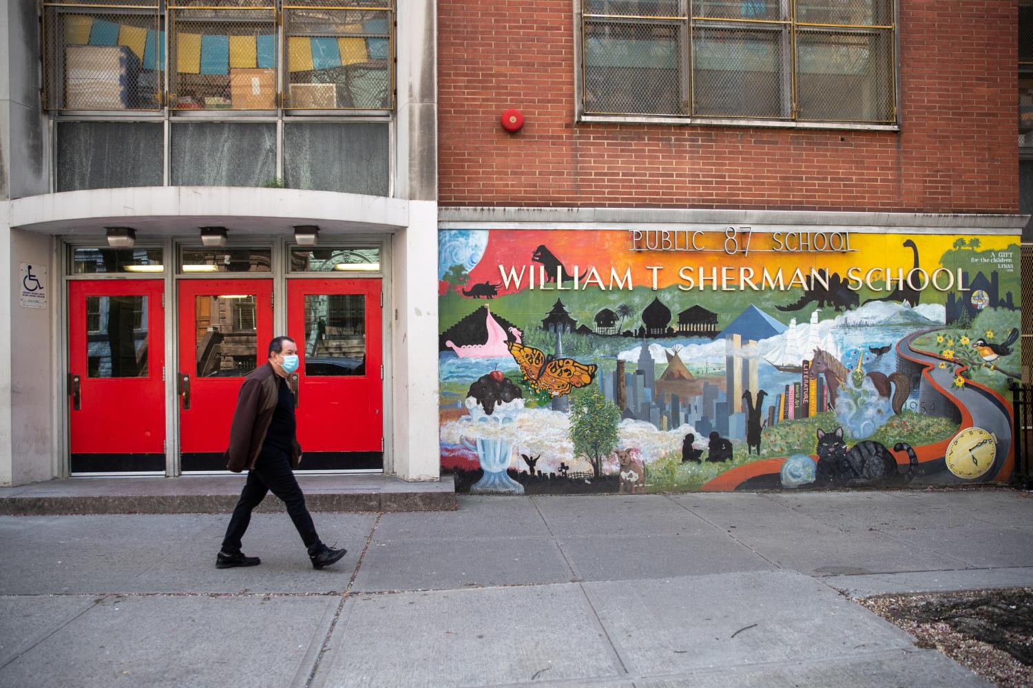 A man wearing a protective mask walks past P.S. 87 William Sherman School during the outbreak of the coronavirus disease (COVID-19) in the Manhattan borough of New York City, New York, U.S., April 12, 2020. REUTERS/Jeenah Moon