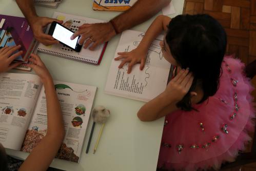 Alice, 5, watches a video sent by school as she studies at home with her father Rodrigo Pinto as his work was suspended during a lockdown imposed by the state government because of the coronavirus disease (COVID-19) outbreak in Santo Andre, Brazil, March 26, 2020. REUTERS/Amanda Perobelli