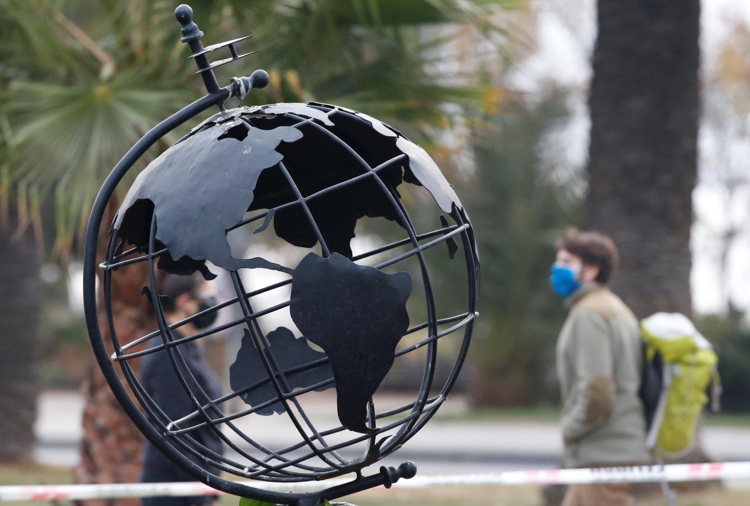 Pedestrians wearing face masks as a precaution against the spread of the coronavirus disease (COVID-19), walk next to a sculpture of the world in a public park in Vina del Mar, Chile April 11, 2020. REUTERS/Rodrigo Garrido