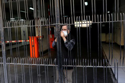 A man wearing a protective mask closes a gate of a parking lot during a quarantine following the outbreak of coronavirus disease (COVID-19), in Santiago, Chile, on April 1, 2020. REUTERS/Pablo Sanhueza