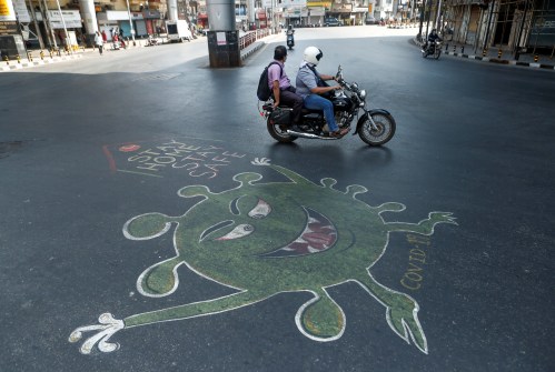 People ride past a graffiti on a road depicting the coronavirus, as an attempt to raise awareness about the importance of staying at home during a nationwide lockdown to slow the spreading of the coronavirus disease (COVID-19), in Mumbai, India, April 20, 2020. REUTERS/Francis Mascarenhas