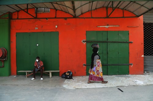 People are pictured in front of closed shops of a market, as the authorities prepare to disinfect the markets amid the outbreak of coronavirus disease (COVID-19) in Abidjan, Ivory Coast March 27, 2020. REUTERS/Luc Gnago