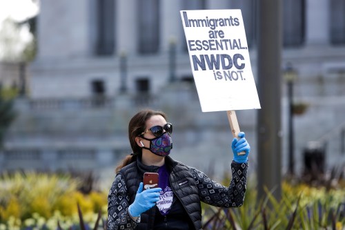 Tae Phoenix of Seattle holds a sign referring to the Northwest Detention Center in Tacoma, Washington where immigrants are held protests outside the Washington state capitol with family and others concerned about the safety and health of inmates as efforts continue to slow the spread of the coronavirus disease (COVID-19) in Olympia, Washington, U.S. April 11, 2020.  REUTERS/Jason Redmond