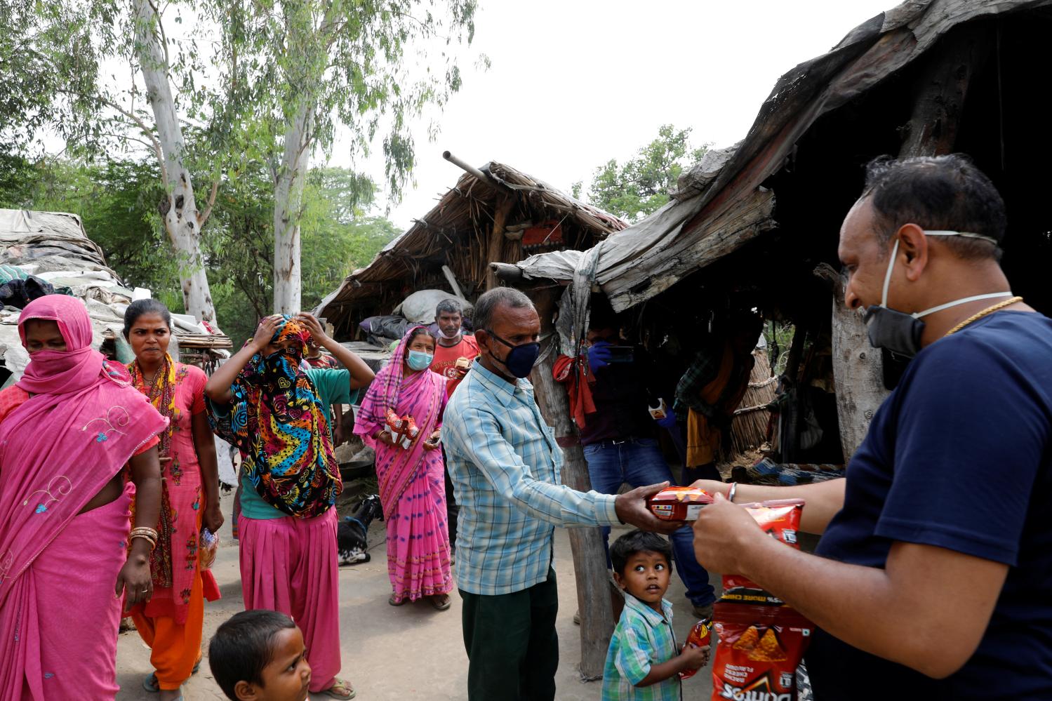 A man distributes food to residents living in a slum on the banks of Yamuna river, during an extended nationwide lockdown to slow the spread of the coronavirus disease (COVID-19), in New Delhi, India, April 29, 2020. REUTERS/Anushree Fadnavis