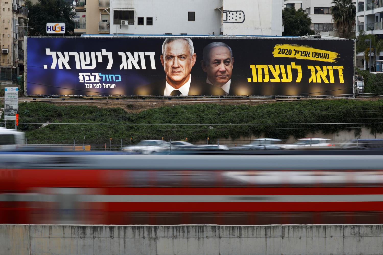 FILE PHOTO: Traffic moves past a Blue and White party election campaign poster, depicting party leader Benny Gantz, and Israeli Prime Minister Benjamin Netanyahu, in Tel Aviv, Israel February 18, 2020. REUTERS/Amir Cohen/File Photo