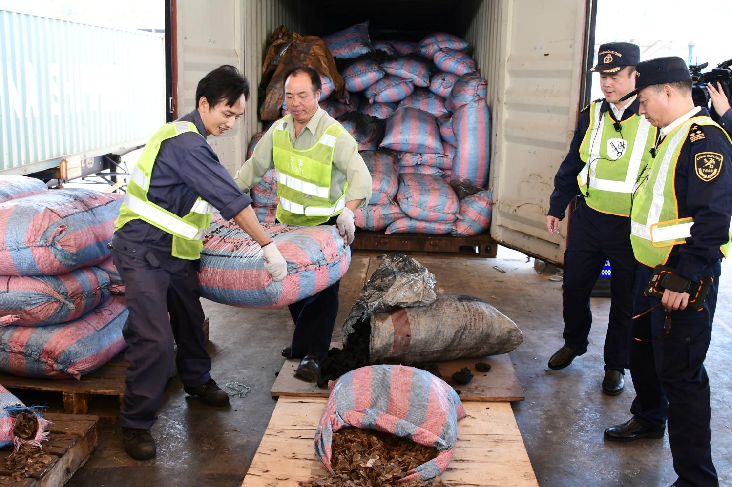 Chinese customs officials carry sacks of pangolins scales they seized on a ship in Shenzhen, Guangdong province, China November 29, 2017. Picture taken November 29, 2017. REUTERS/Stringer ATTENTION EDITORS - THIS IMAGE WAS PROVIDED BY A THIRD PARTY. CHINA OUT.