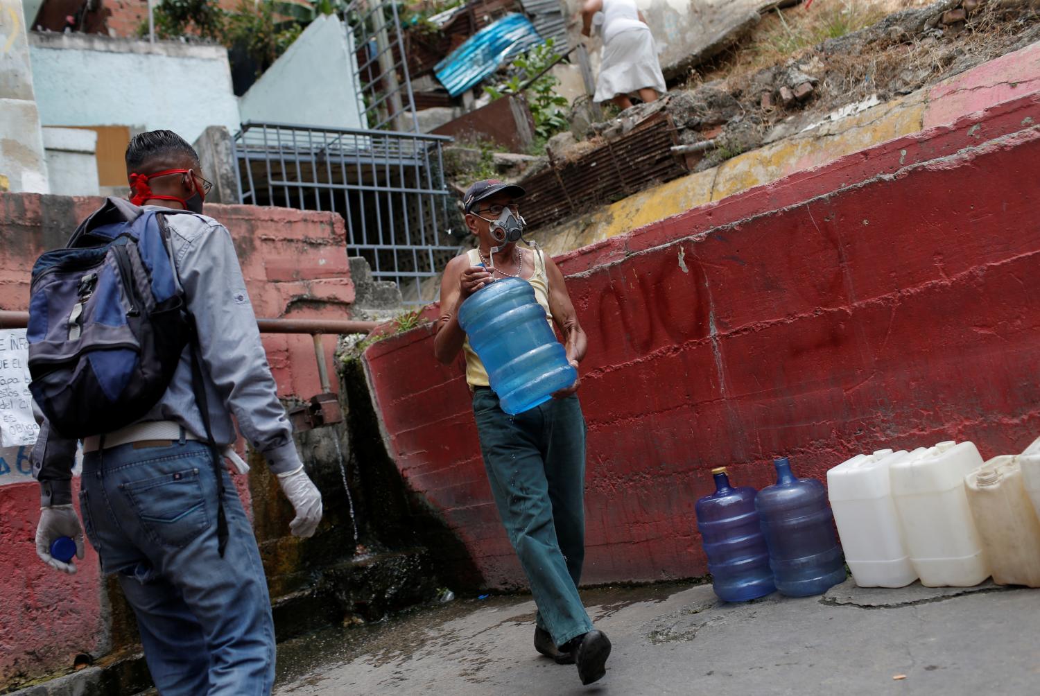 An elder carry a plastic container filled with water from a pipe in a street of a slum during a nationwide quarantine due to coronavirus disease (COVID-19) outbreak in Caracas, Venezuela April 2, 2020. Picture taken April 2, 2020. REUTERS/Manaure Quintero