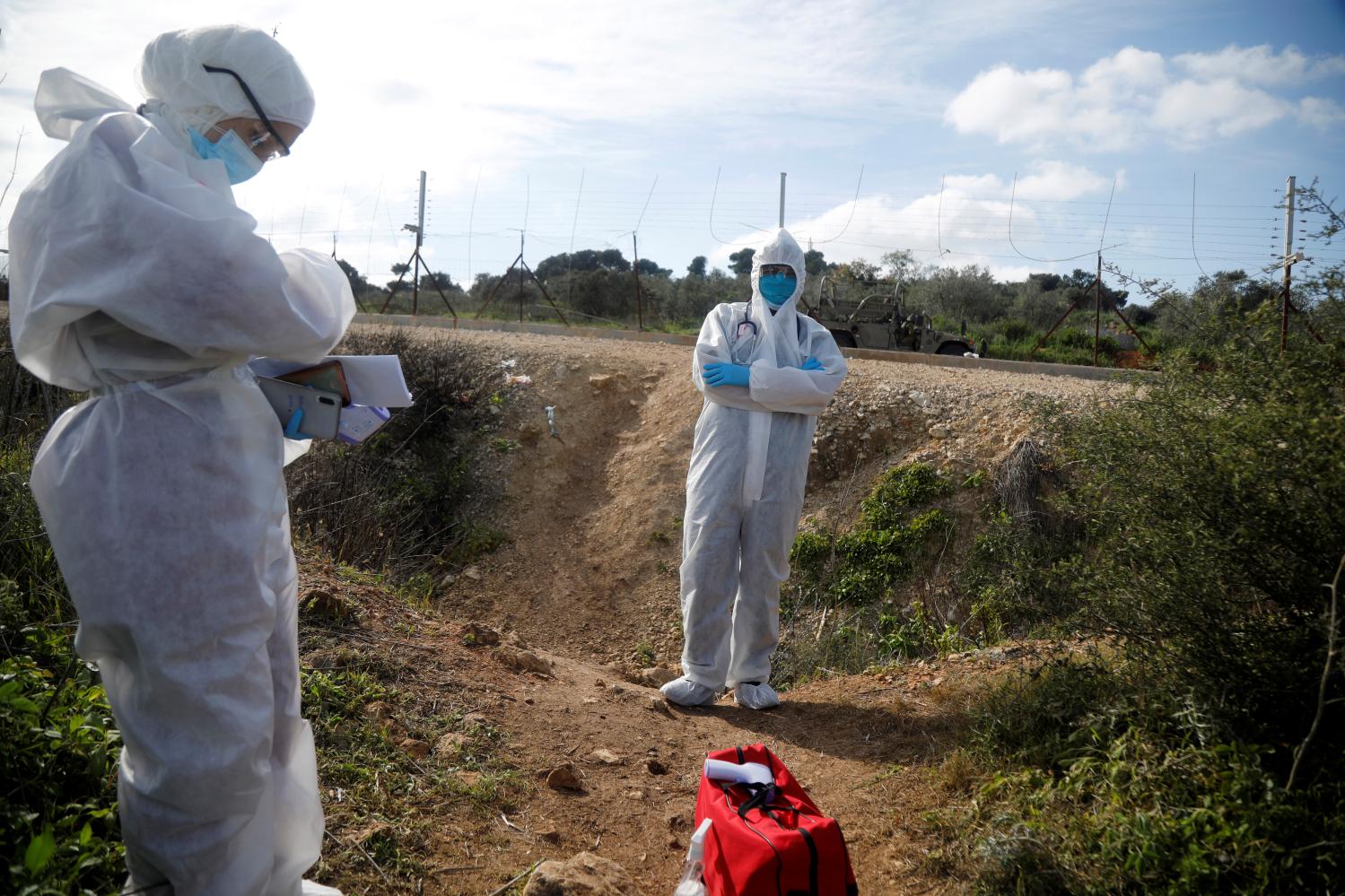 Healthcare workers watch for Palestinian labourers, who sneak back into the West Bank from Israel as they do not have permits, to test them for coronavirus infection, in the Israeli-occupied West Bank April 7, 2020. Picture taken April 7, 2020. REUTERS/Raneen Sawafta