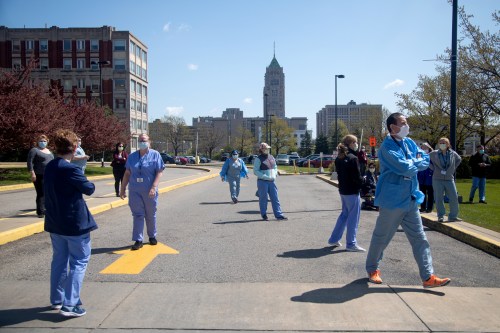 Healthcare workers gather outside the main entrance of Henry Ford Hospital to watch the U.S. Navy Blue Angels' flyover as a salute to frontline workers amid an outbreak of the coronavirus disease (COVID-19) in Detroit, Michigan, U.S., May 12, 2020. REUTERS/Emily Elconin