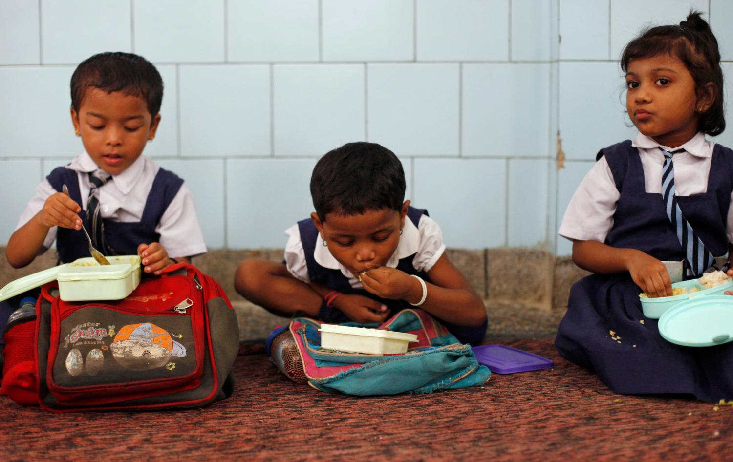 Schoolgirls eat their free mid-day meal, distributed by a government-run primary school, in New Delhi July 5, 2013. In an incident on July 16, 2013, twenty-five Indian children from a school in Mashrakh village in the district of Chapra died and dozens needed hospital treatment after apparently being poisoned by a school meal, provided under the Mid-Day Meal Scheme, sparking violent protests and angry allegations of blame. Neither the children nor the school pictured in this photograph were involved in Tuesday's poisoning incident. ATTENTION EDITORS - Neither the children nor the school pictured in this photograph were involved in Tuesday's poisoning incident. Picture taken July 5, 2013. REUTERS/Mansi Thapliyal (INDIA - Tags: FOOD EDUCATION SOCIETY)