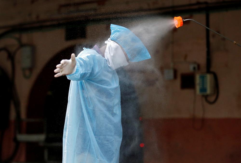 A municipal worker is sanitized after he cremated the body of a man, who died due to coronavirus disease (COVID-19), at a crematorium in Ahmedabad, India, April 22, 2020. REUTERS/Amit Dave - RC2R9G9CNWP2