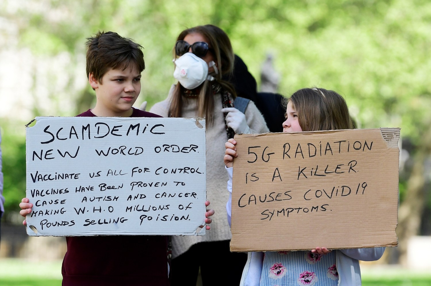 People hold up banners in protest against lockdown and vaccination outside New Scotland Yard police headquarters, following the outbreak of the coronavirus disease (COVID-19), London, Britain, May 2, 2020. REUTERS/Toby Melville