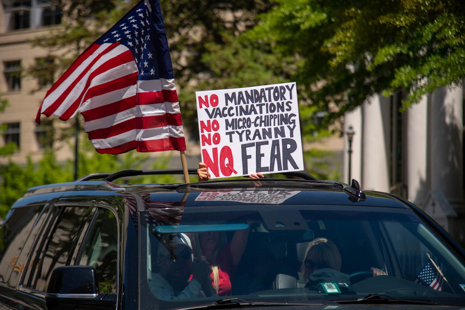A woman holds a sign voicing various conspiracy theories believed by QAnon followers out of the sunroof of a car at the "Reopen Virginia" protest in Richmond on April 22nd, 2020.  Three Percenters are a movement that advocates for constitutional rights, and takes its name from the belief that only three percent of America took up arms against the British during the Revolutionary War. (Photo by Matthew Rodier/Sipa USA)No Use UK. No Use Germany.