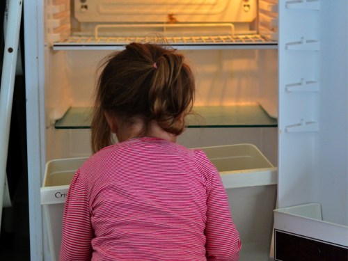 little girl looking through empty fridge