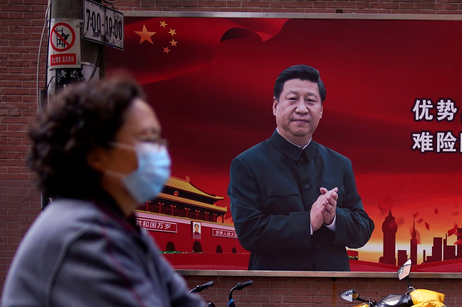 FILE PHOTO: A woman wearing a protective mask is seen past a portrait of Chinese President Xi Jinping on a street as the country is hit by an outbreak of the coronavirus, in Shanghai, China March 12, 2020. REUTERS/Aly Song/File Photo
