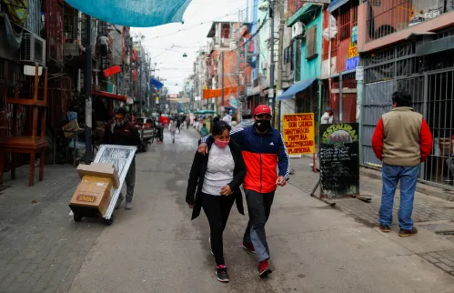 A couple wearing protective face masks walk along the Villa 31 slum, as the spread of the coronavirus disease (COVID-19) continues, in Buenos Aires, Argentina May 6, 2020. REUTERS/Agustin Marcarian
