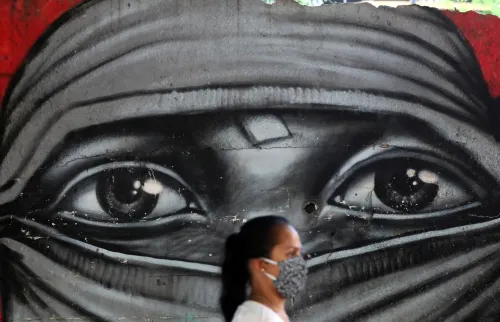 A woman wearing a protective mask walks in front of a graffiti, amid the coronavirus disease (COVID-19) outbreak in Rio de Janeiro, Brazil, May 13, 2020. REUTERS/Sergio Moraes