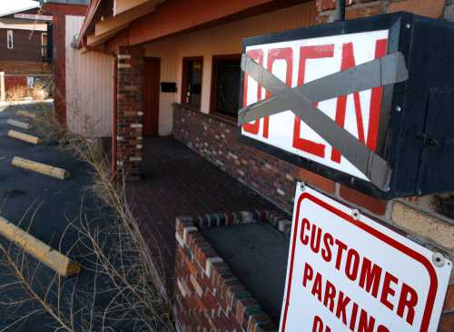 Weeds are seen near a sign hanging outside a bar that went out of business in Denver February 26, 2009.  REUTERS/Rick Wilking (UNITED STATES)