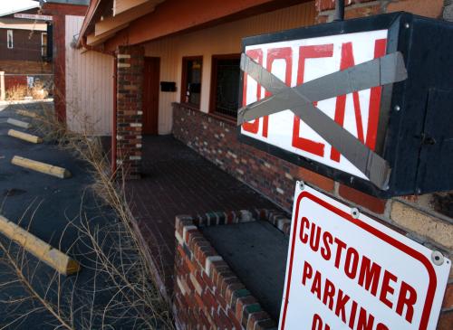 Weeds are seen near a sign hanging outside a bar that went out of business in Denver February 26, 2009.  REUTERS/Rick Wilking (UNITED STATES)