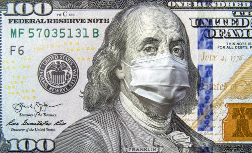 COVID-19 coronavirus in USA, 100 dollar money bill with face mask. Coronavirus affects global stock market. World economy hit by corona virus outbreak and pandemic fears. Crisis and finance concept.