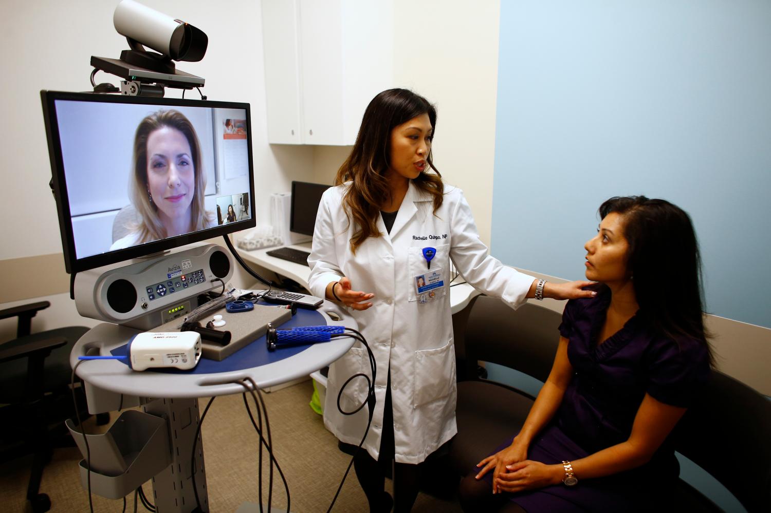 Nurse Health Practitioner Rachelle Quimpo (C) introduces patient Shreya Sasaki to Dr. Heidi Meyer, MD Family Medicine, who appears on a video screen remotely at a newly opened Kaiser Permanente health clinic inside a Target retail department store in San Diego, California November 17, 2014. Four clinics are scheduled to open in Southern California to provide pediatric and adolescent care, well-woman care, family planning, and management of chronic conditions like diabetes and high blood pressure for Kaiser members and non-members. REUTERS/Mike Blake (UNITED STATES - Tags: HEALTH BUSINESS SOCIETY)