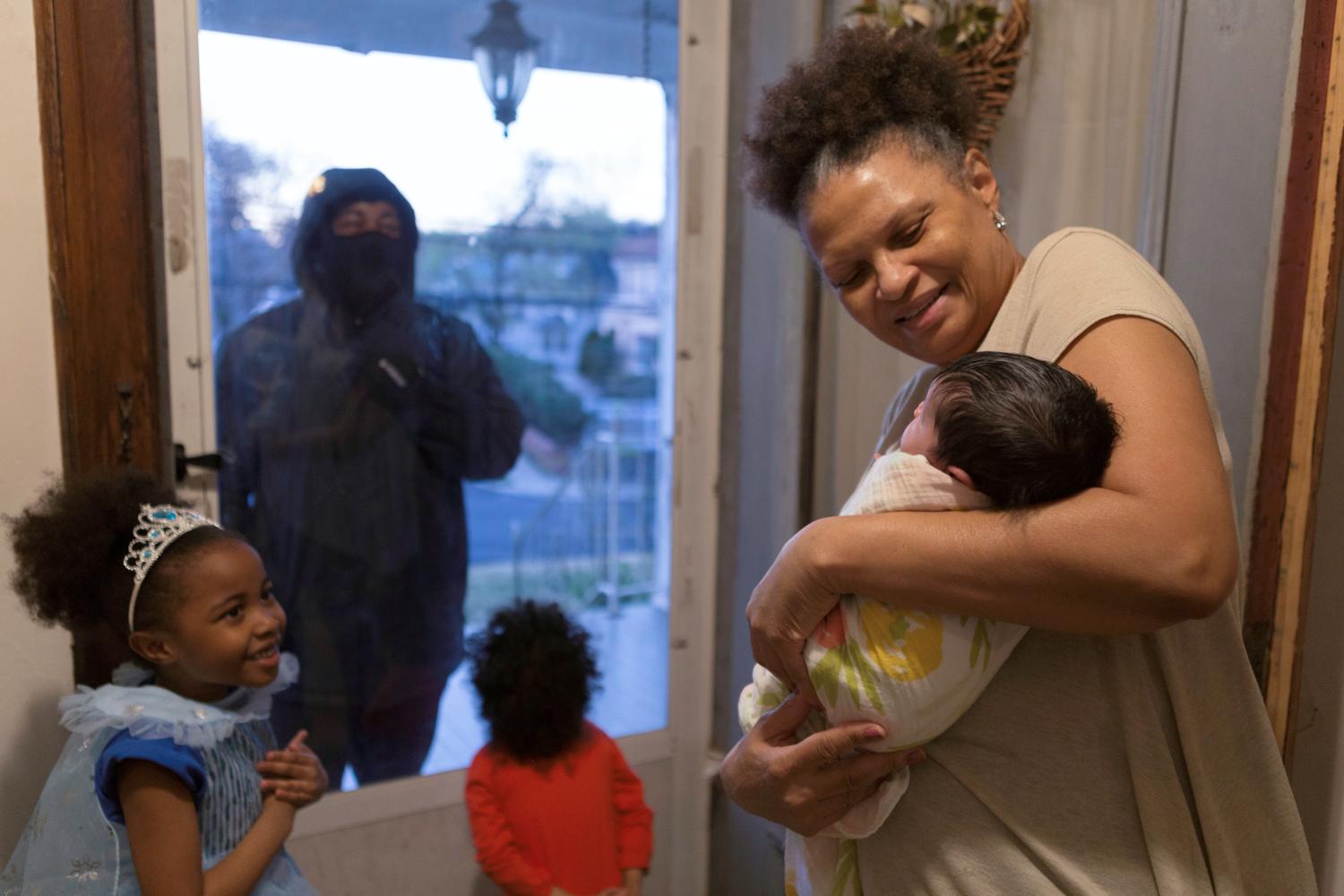 Hashim, an essential worker in the healthcare industry, sees his newborn niece for the first time as he greets his daughter and nephew through the closed door as he maintains social distance from his family as he works amid the coronavirus disease (COVID-19) outbreak in New Rochelle, New York, U.S., April 20, 2020. Picture taken April 20, 2020.  REUTERS/Joy Malone