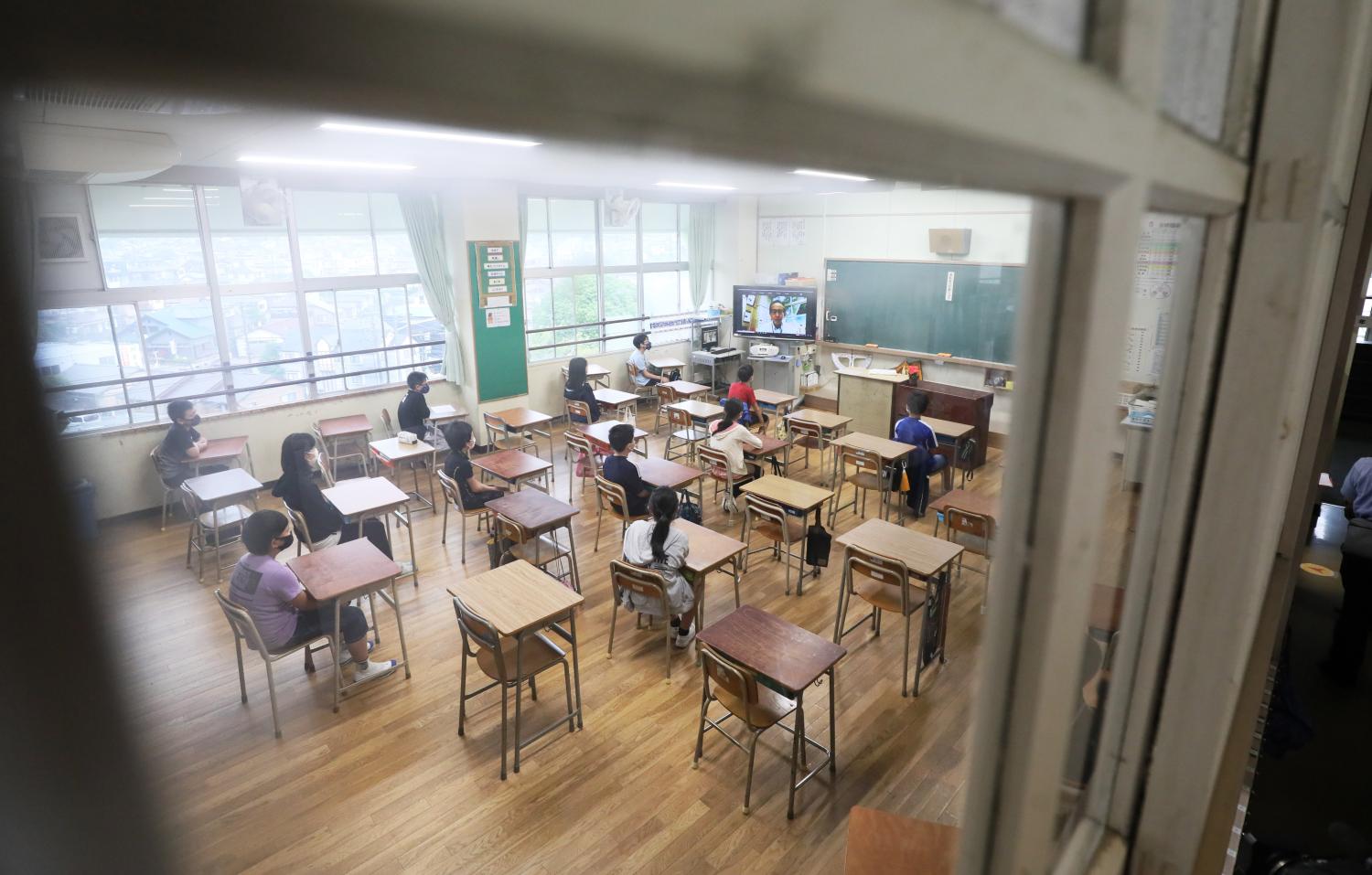 Students listen to a greeting from a principal through TV class at an elementary school, where students found positve for a new coronavirus test, in Kitakyushu, Fukuoka Prefecture on June 18, 2020. The elmenatary school decided to operate the staggered attendance to prevent the spread of Covid-19 infection. ( The Yomiuri Shimbun )