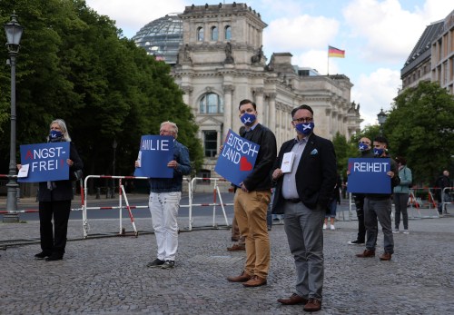 People wearing face masks hold signs and copies of the German constitution as they participate in a protest by the Alternative for Germany (AfD) party against the government's restrictions following the coronavirus disease (COVID-19) outbreak, in Berlin, Germany, May 16, 2020. REUTERS/Fabrizio Bensch
